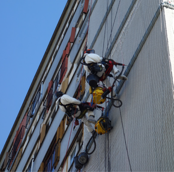 cordistes travaillant en hauteur sur la façade d'un immeuble