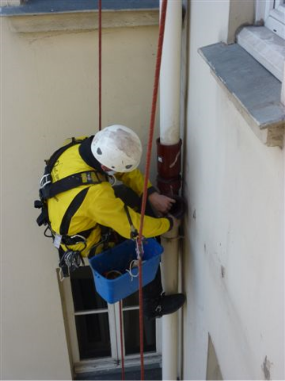 cordiste travaillant accroché à une gouttière